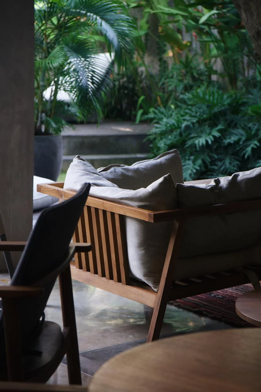 Outdoor terrace with custom wooden furniture and lush garden setting, Surf Motel Canggu